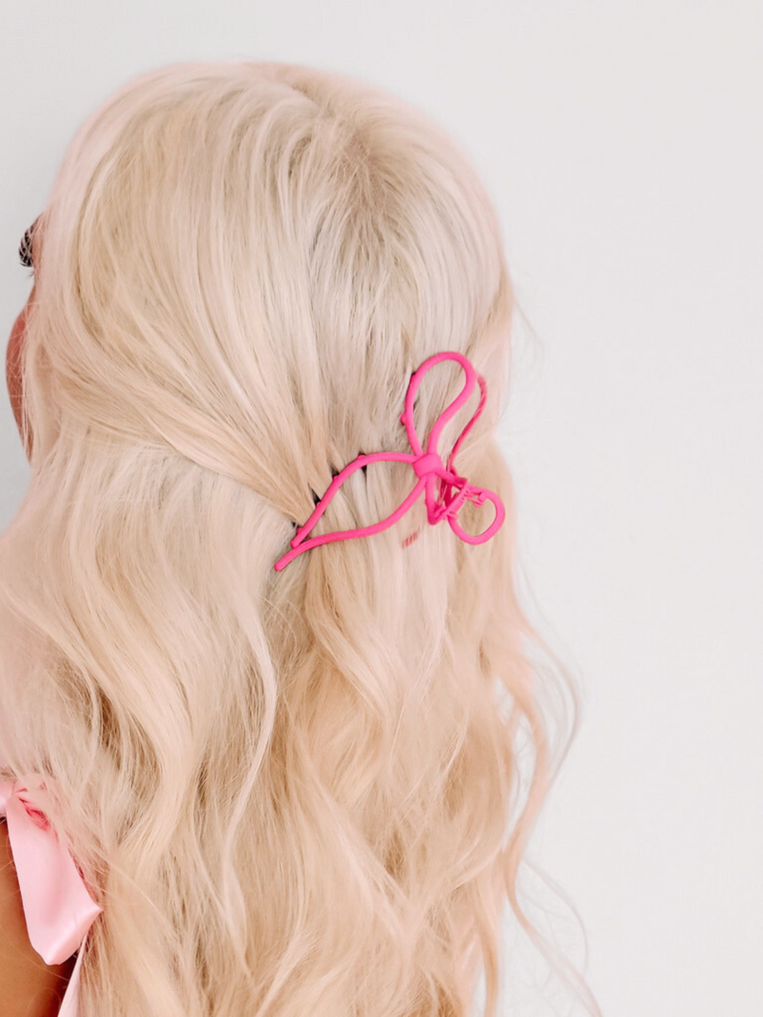 Pink Take A Bow claw clip in blonde hair.
