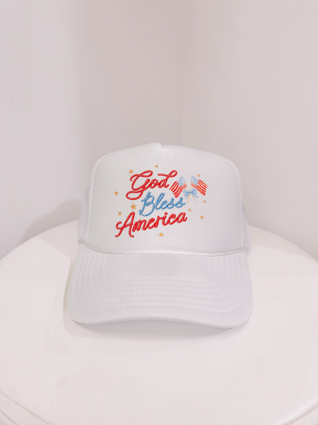 White trucker hat with "God Bless America" embroidery and small patriotic flags from sassy shortcake
