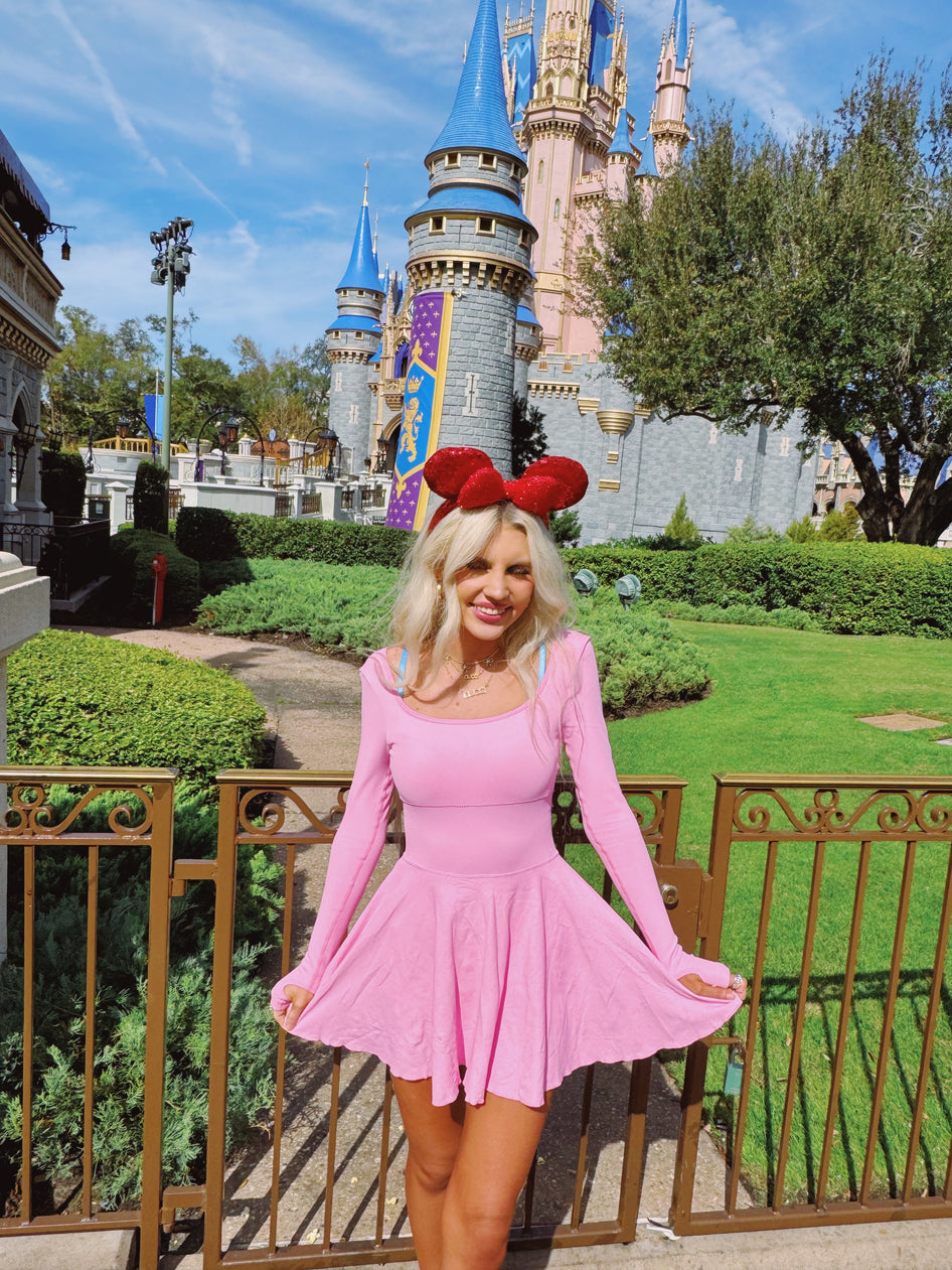 Pink skater dress worn at a park with a fairytale castle in the background.
