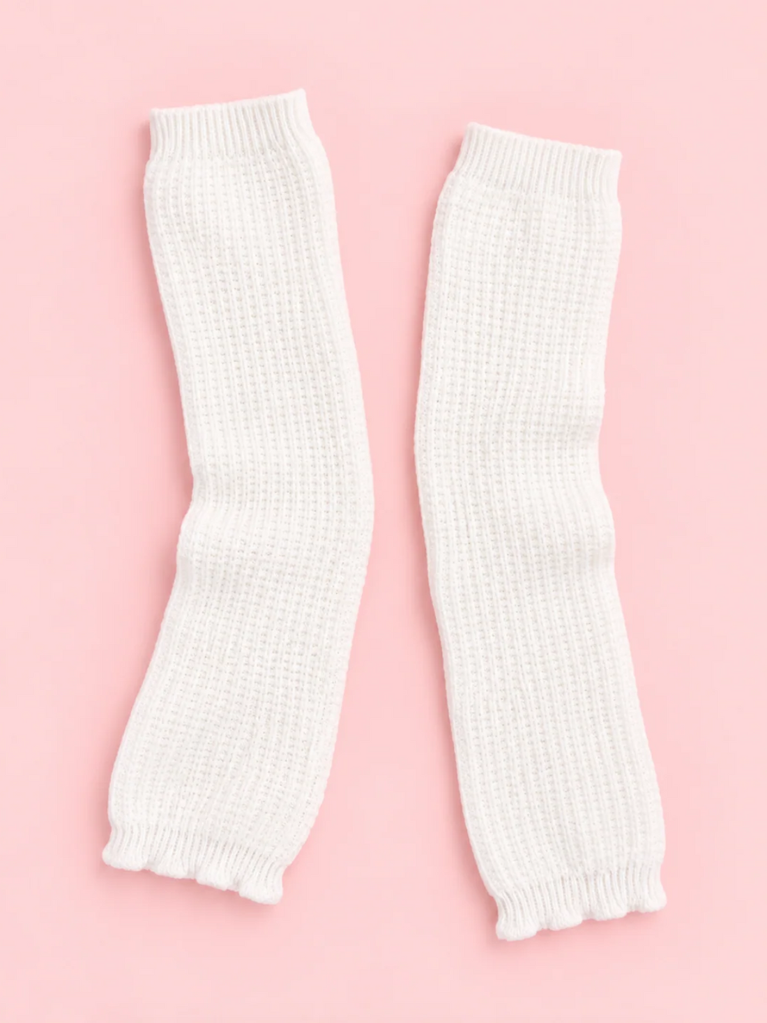 Pair of white Fireside Waffle Knit Leg Warmers with ribbed cuffs laid flat on a pink background from sassy shortcake