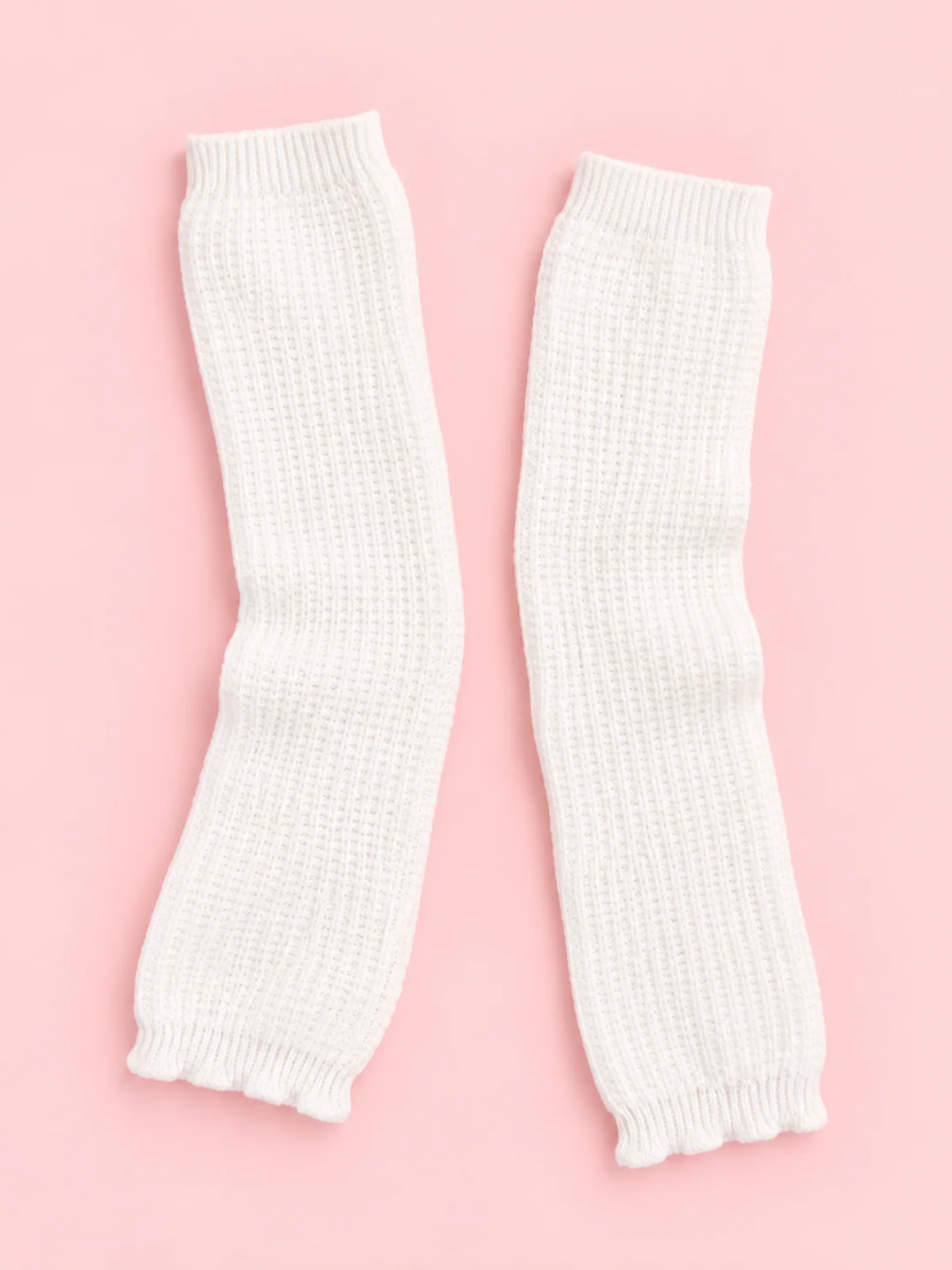 Pair of white Fireside Waffle Knit Leg Warmers with ribbed cuffs laid flat on a pink background from sassy shortcake