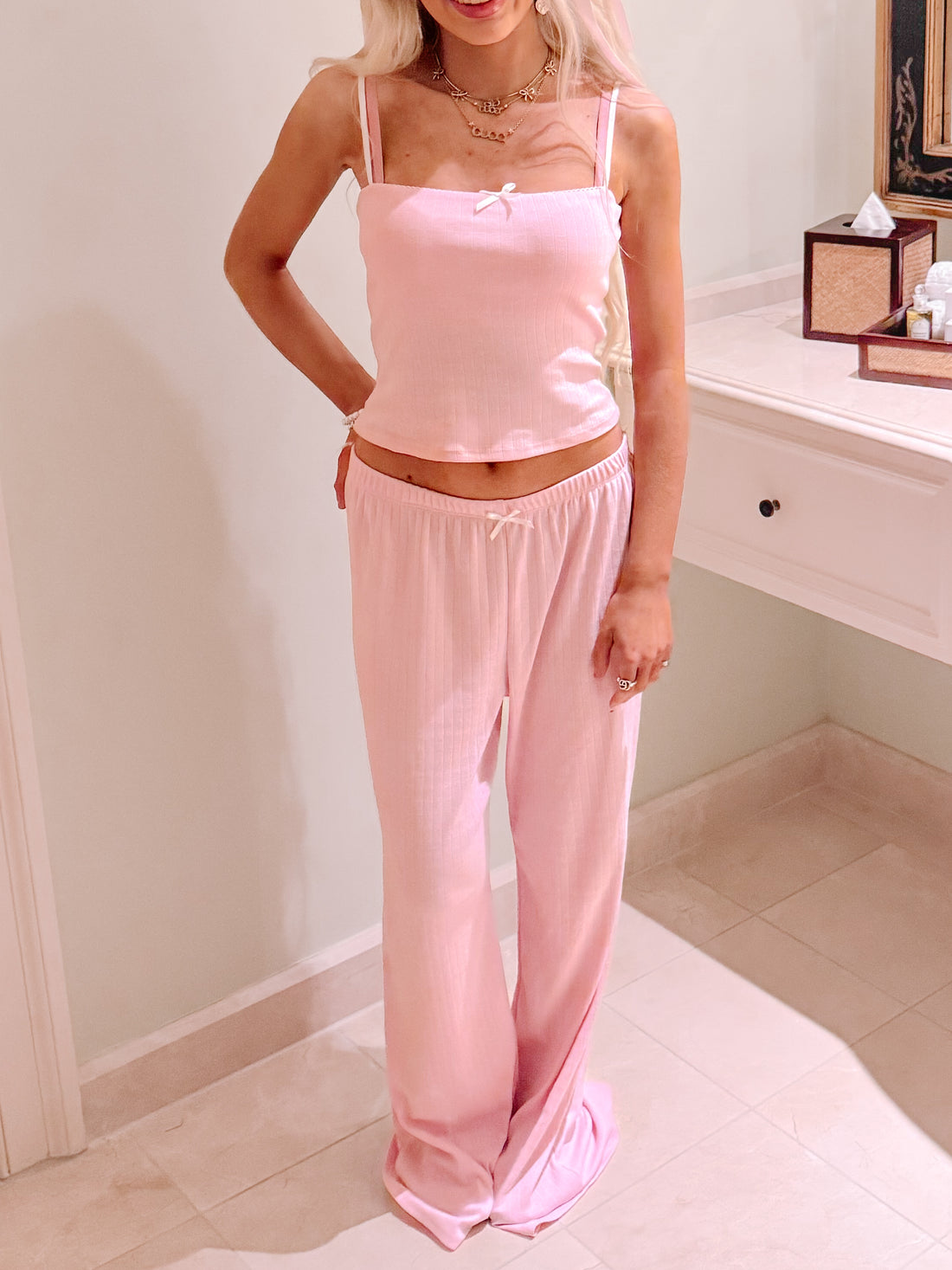 Pink pajama set; ribbed tank top and wide-leg pants, bow details.
