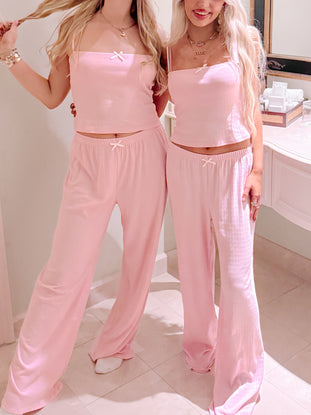 Pink pajama set with wide-leg pants and cropped tank top, featuring delicate bows.
