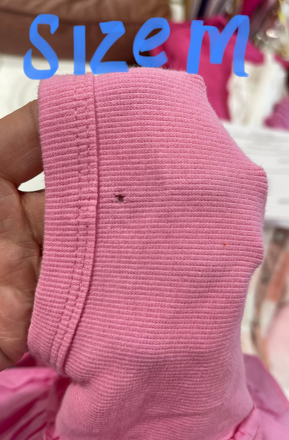 Close-up of pink ribbed fabric showing texture and minor imperfection.

