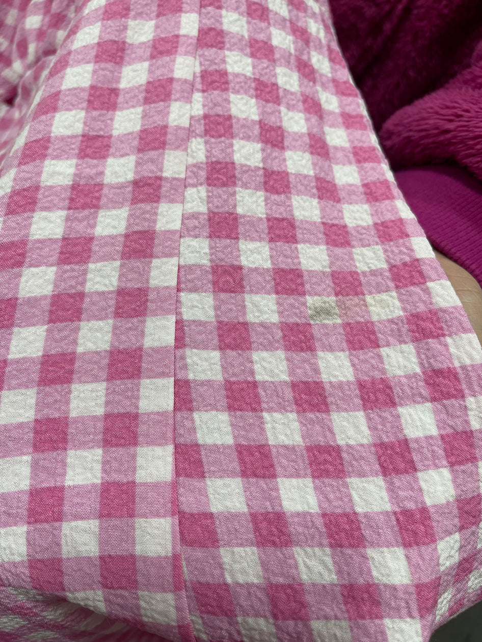 Pink and white gingham fabric detail, textured weave.
