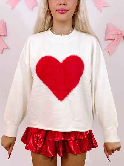 Cream oversized sweater with a fluffy red heart detail.
