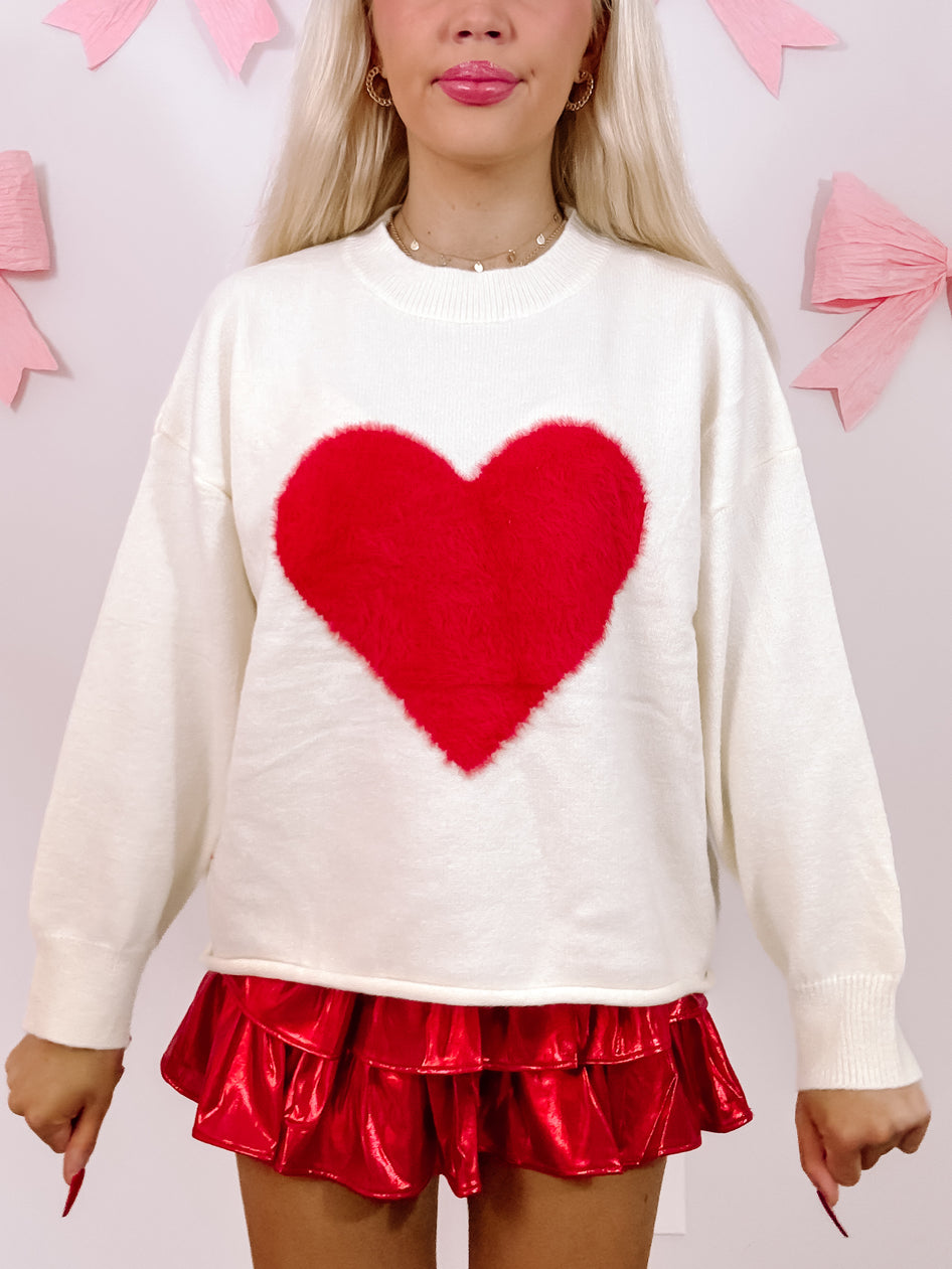 Cream oversized sweater with a large fluffy red heart detail.
