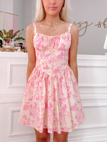 Pink floral mini dress with a fitted bodice and flowy skirt, shown on a model.
