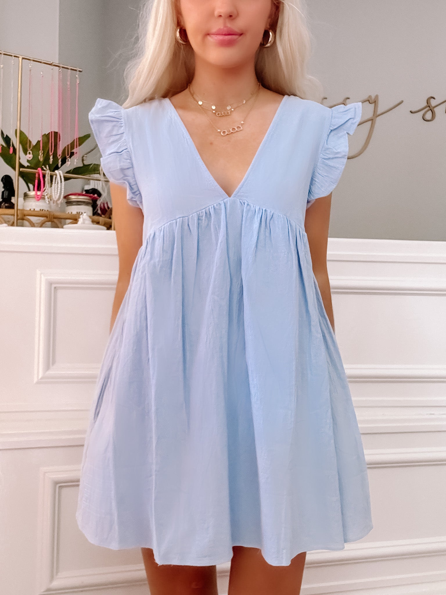 Light blue mini dress with ruffled sleeves, V-neckline, and a relaxed fit.
