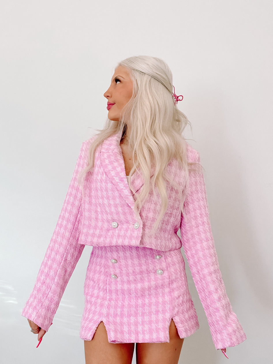 Pink tweed skirt suit; cropped jacket & mini skirt with pearl buttons.

