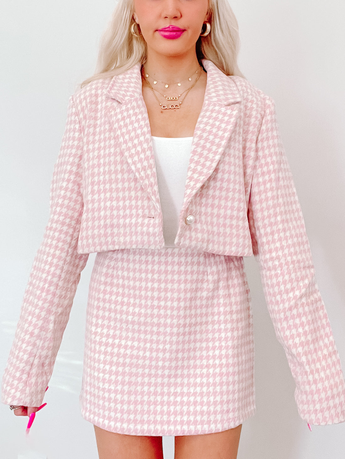 Pink houndstooth cropped blazer and skirt set; stylish, textured fabric.

