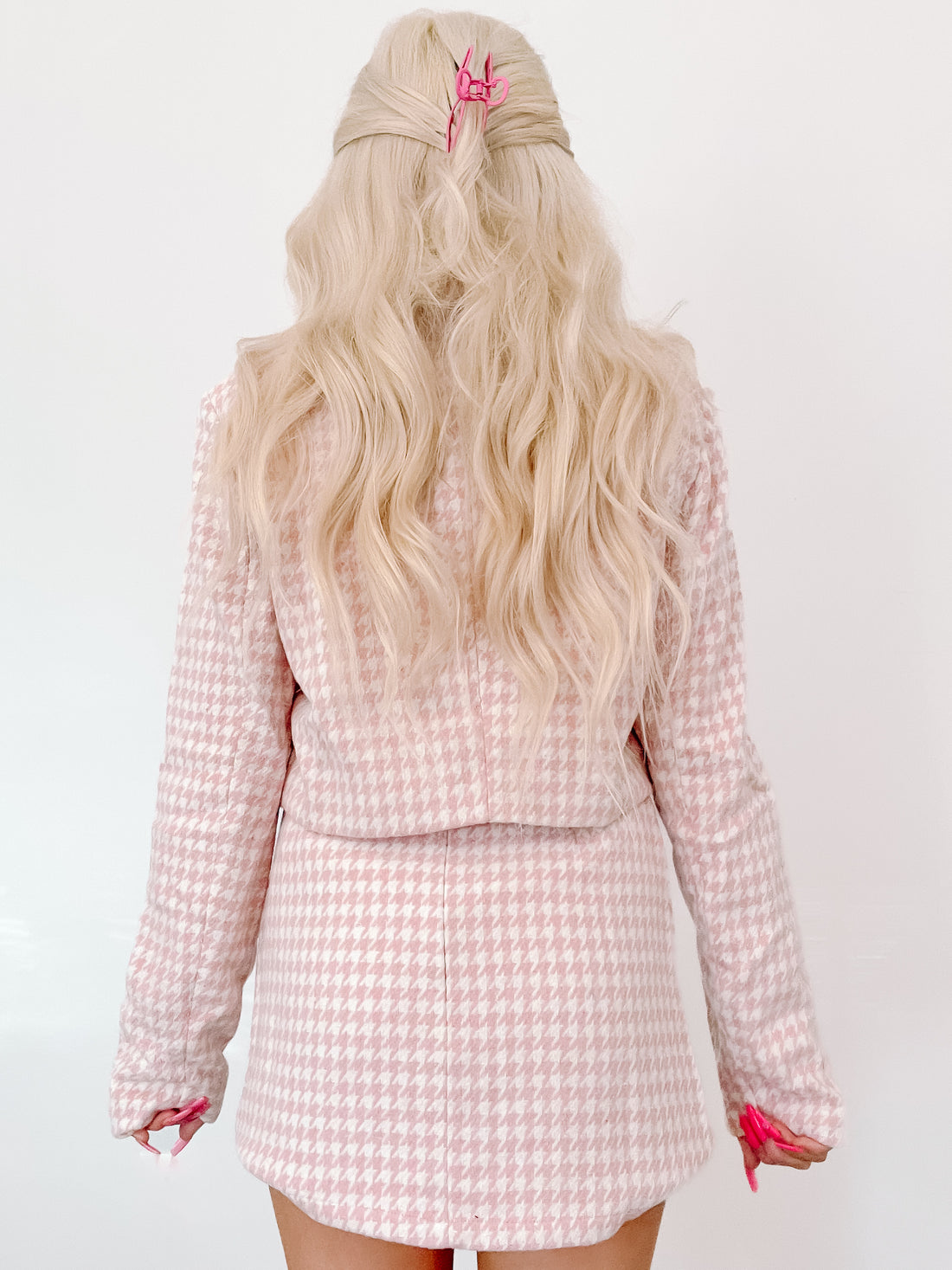 Houndstooth-patterned pink blazer and skirt set, shown from the back on a model.
