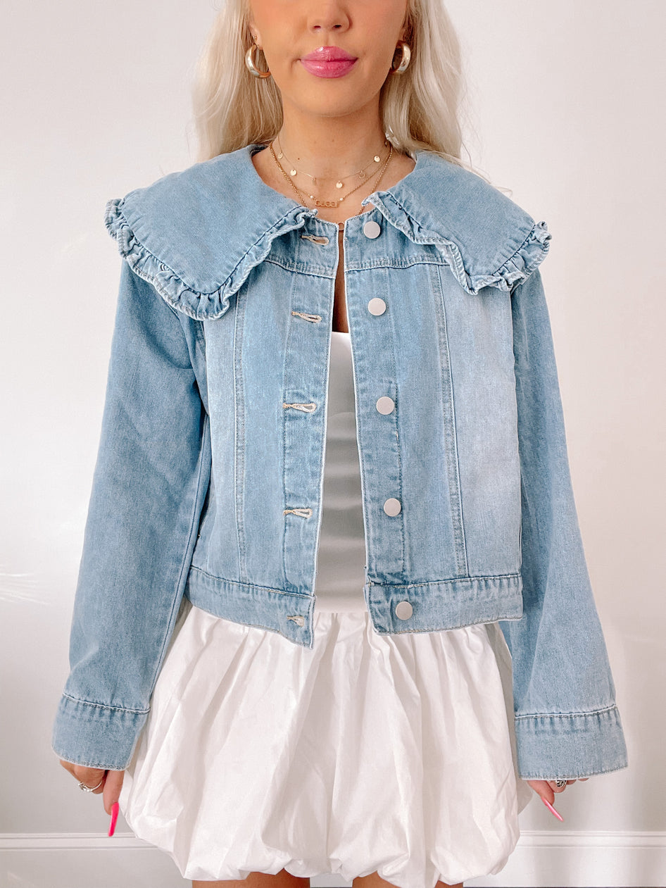 Light wash denim jacket featuring a ruffled Peter Pan collar; styled with a white bubble skirt.
