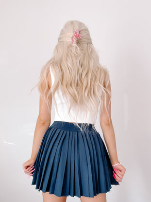 Navy blue pleated tennis skirt shown from behind on a model.
