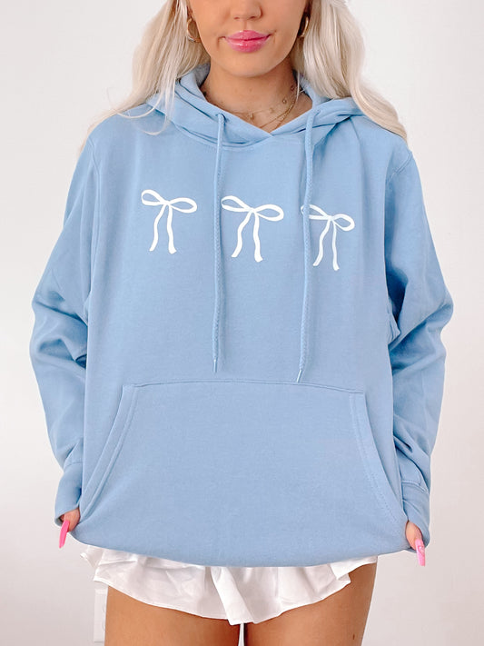 Light blue hoodie featuring three white bows, casual style.