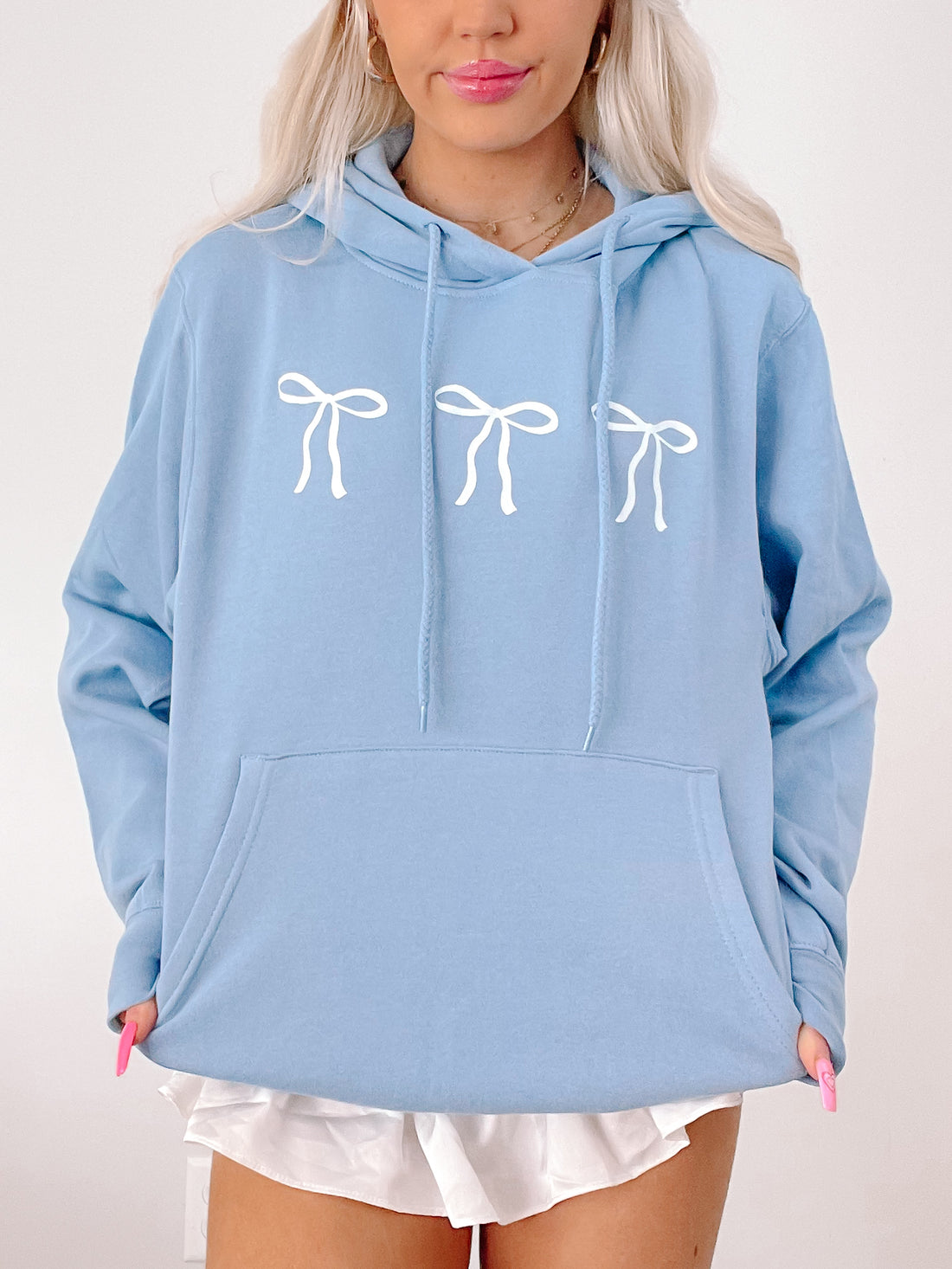 Light blue hoodie featuring three white bows, casual style.
