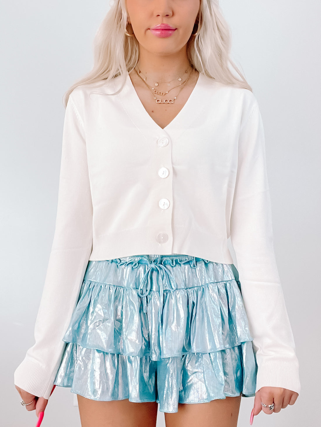 Cream button-front cardigan paired with a shimmering teal ruffle skirt.
