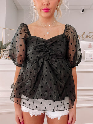Black polka dot sheer top with puff sleeves and a sweetheart neckline.
