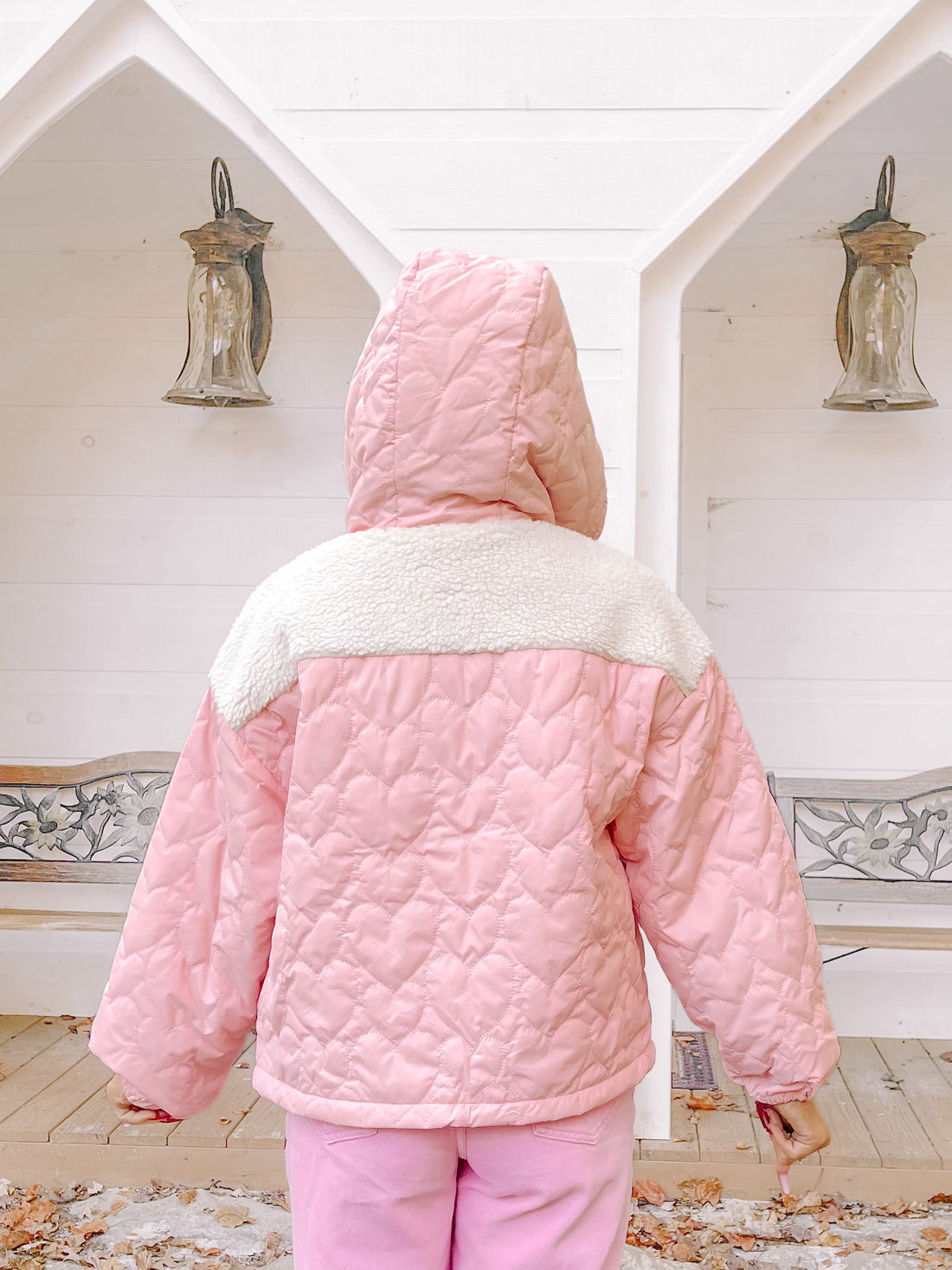 Pink quilted heart-pattern jacket with cream sherpa collar, shown outdoors.
