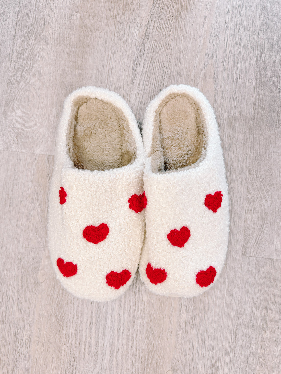 Cozy white slippers with red heart details, perfect for relaxing at home.
