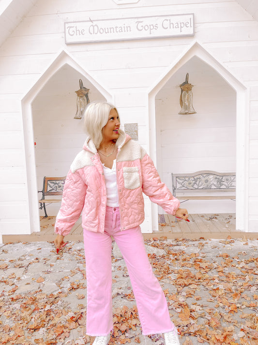 Pink quilted jacket styled outdoors, featuring sherpa trim and worn with pink pants.