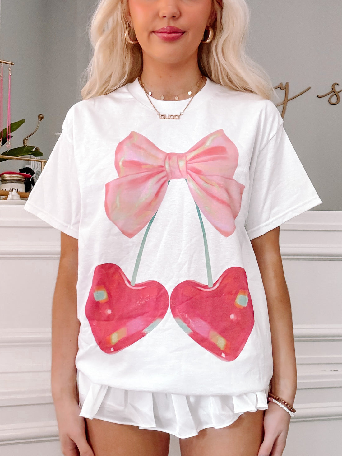 White Cherry Bow Tee featuring a pink bow and two cherries.
