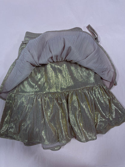 Gold shimmering mini skirt with ruffled hem, shown inside out on a pale pink background.
