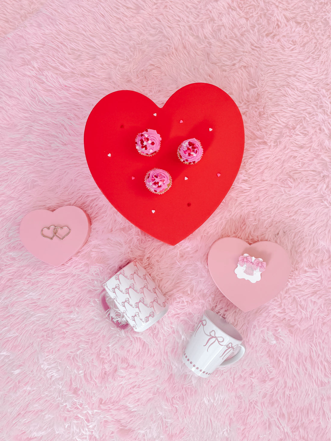 White mug with pink ribbon design, on pink fluffy surface.
