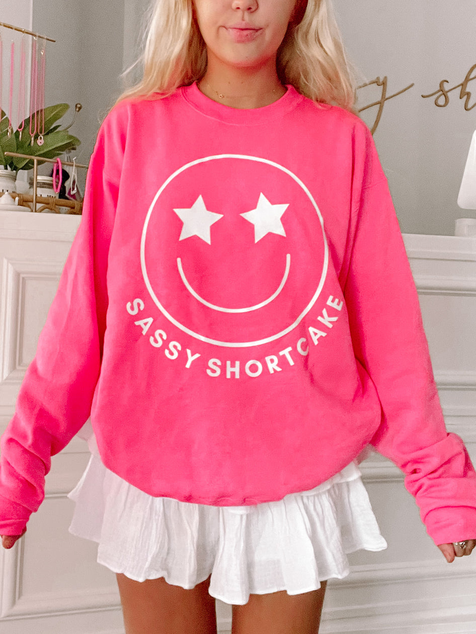 Hot pink Sassy Shortcake Smiley crewneck sweatshirt with white star-eye smiley face graphic.
