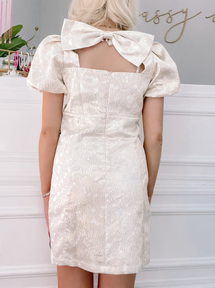 Gold Let it Bow Dress:  Elegant off-white mini dress with puff sleeves & back bow detail.
