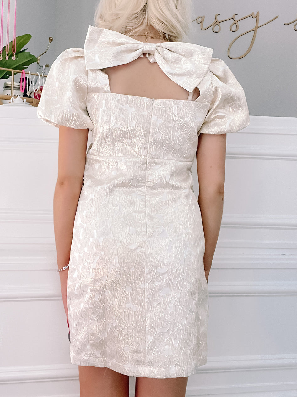 Gold Let it Bow Dress:  Elegant off-white mini dress with puff sleeves & back bow detail.
