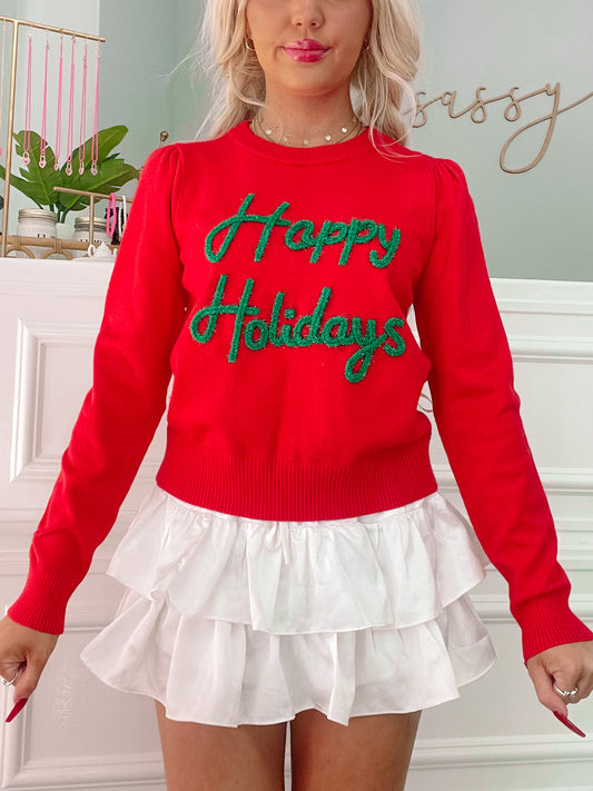 Red crewneck sweater with green sparkly "Happy Holidays" lettering.
