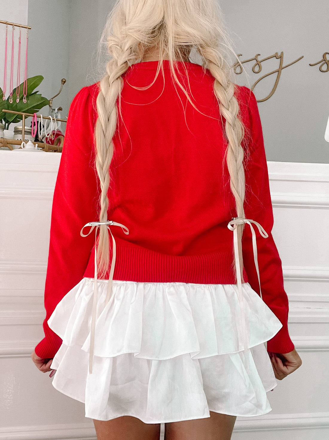 Red sweater with white ruffle skirt, styled with braided blonde hair.
