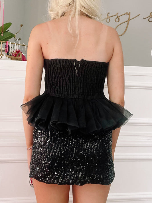 Black sequin mini skirt and sheer black ruffled crop top ensemble.