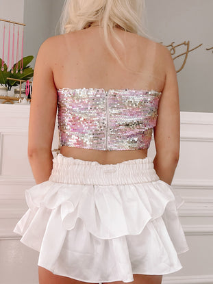 Pastel sequin crop top paired with a white ruffled mini skirt.
