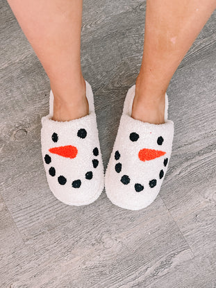 Cozy snowman slippers on a wood floor.
