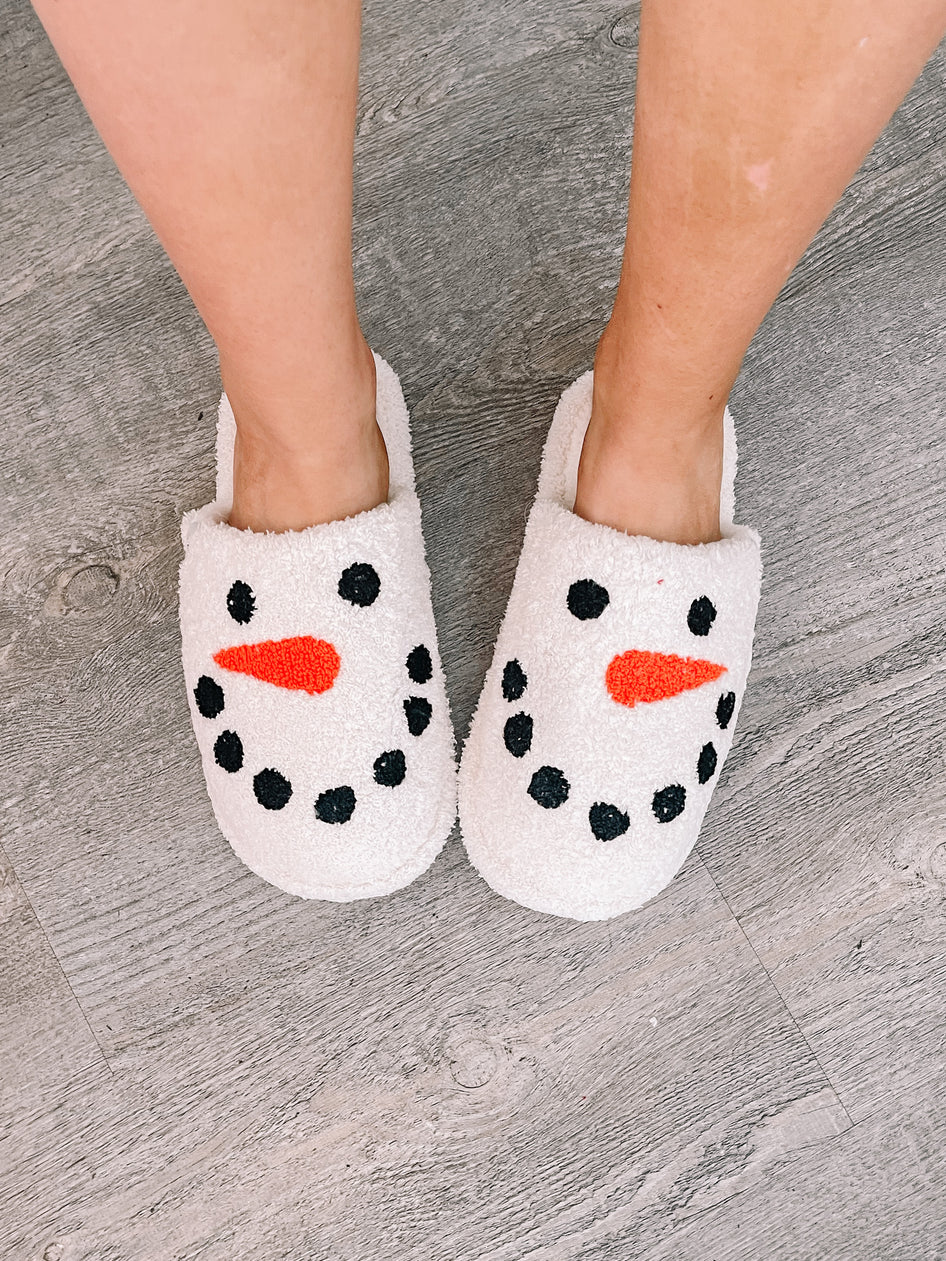 Cozy snowman slippers on a wood floor.
