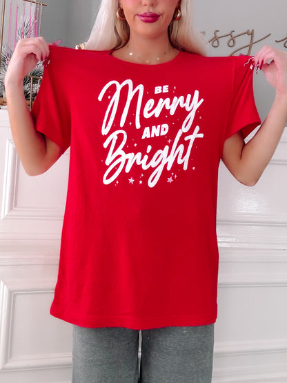Person wearing a red t-shirt with 'Be Merry and Bright' text.