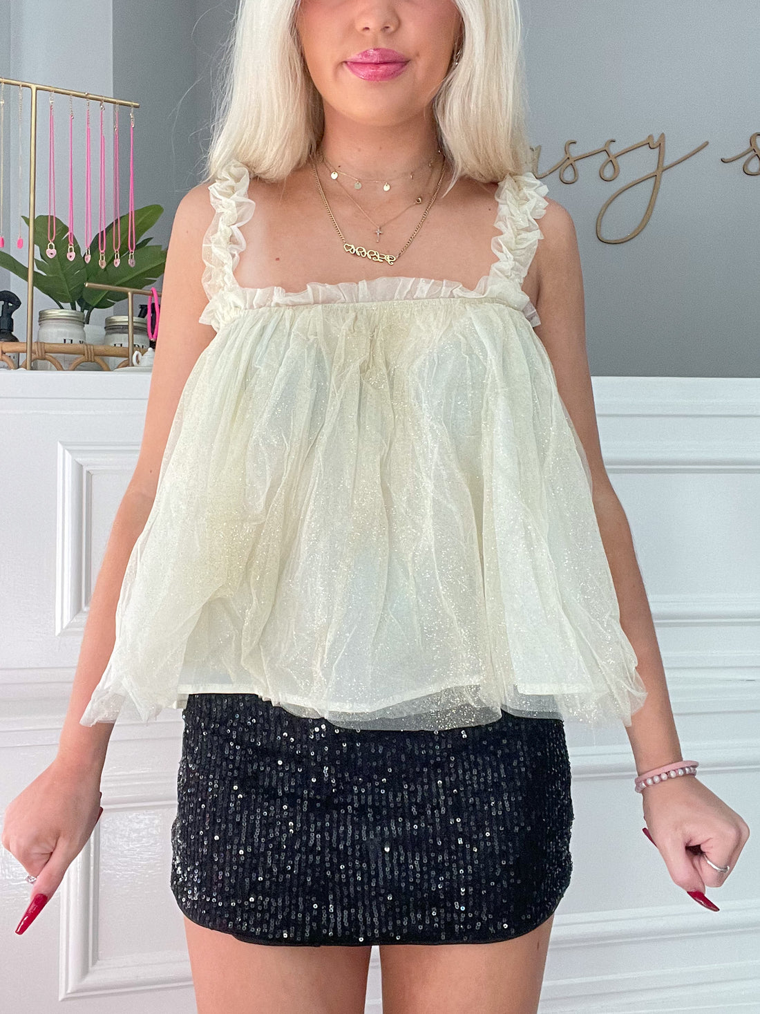 Pale yellow glitter tulle top with ruffle straps, styled with a sequined mini skirt.
