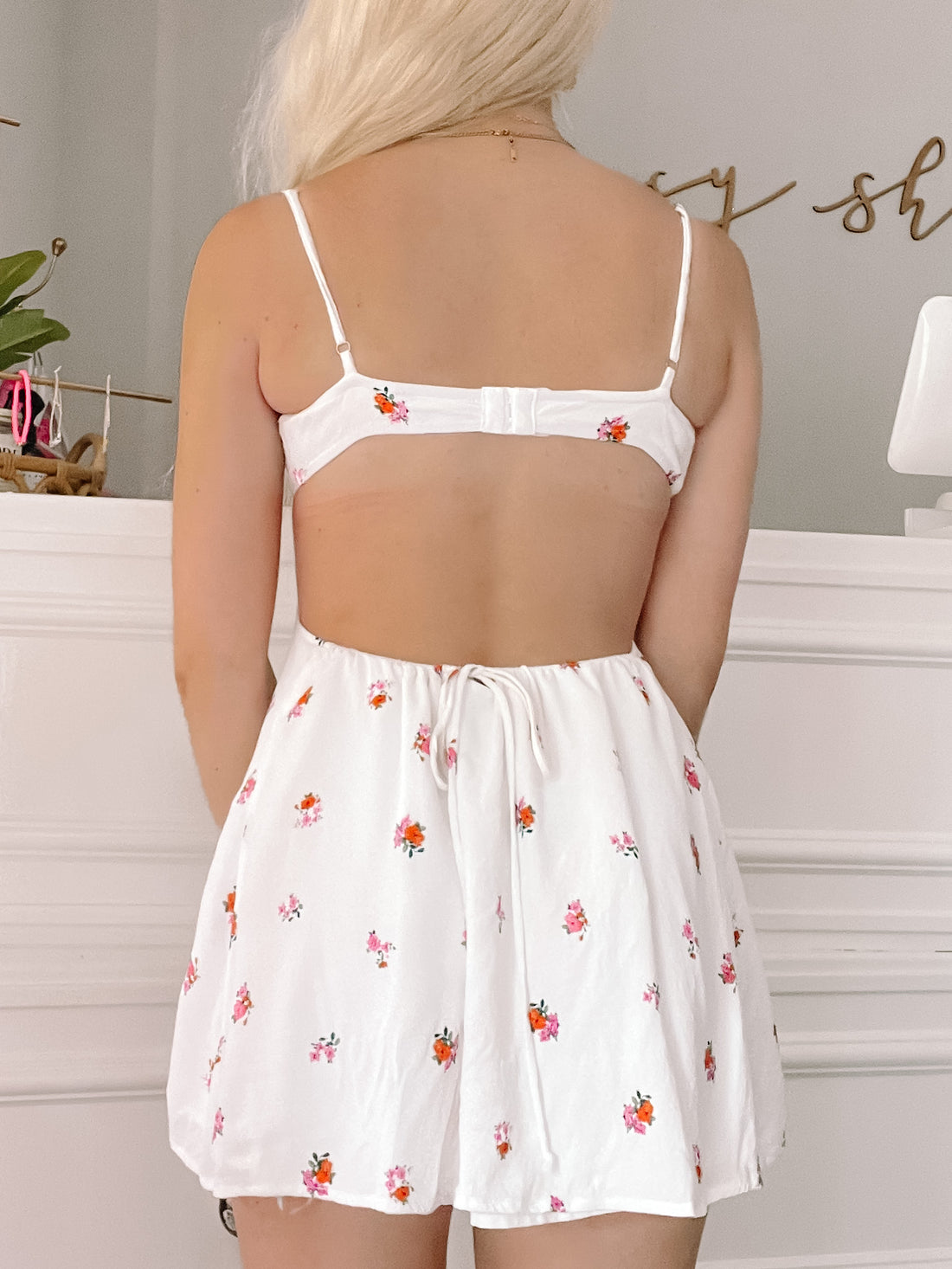 White floral mini dress with open back detail and drawstring waist.
