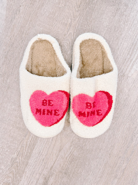 Cozy "Be Mine" heart slippers; cream fuzzy fabric with pink heart design.
