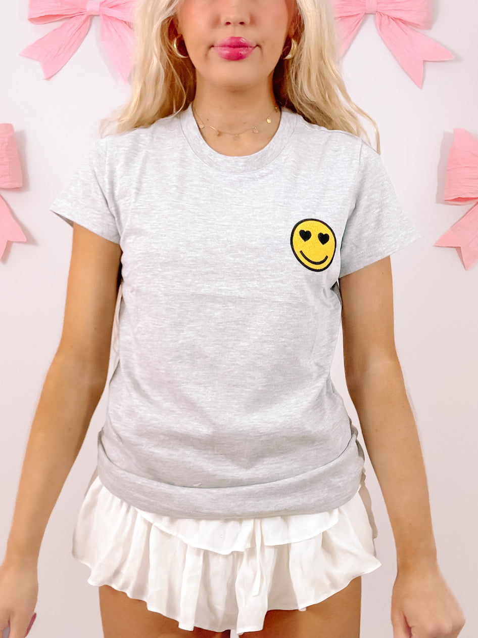 Grey Happy Heart Tee featuring a cute embroidered smiley face.
