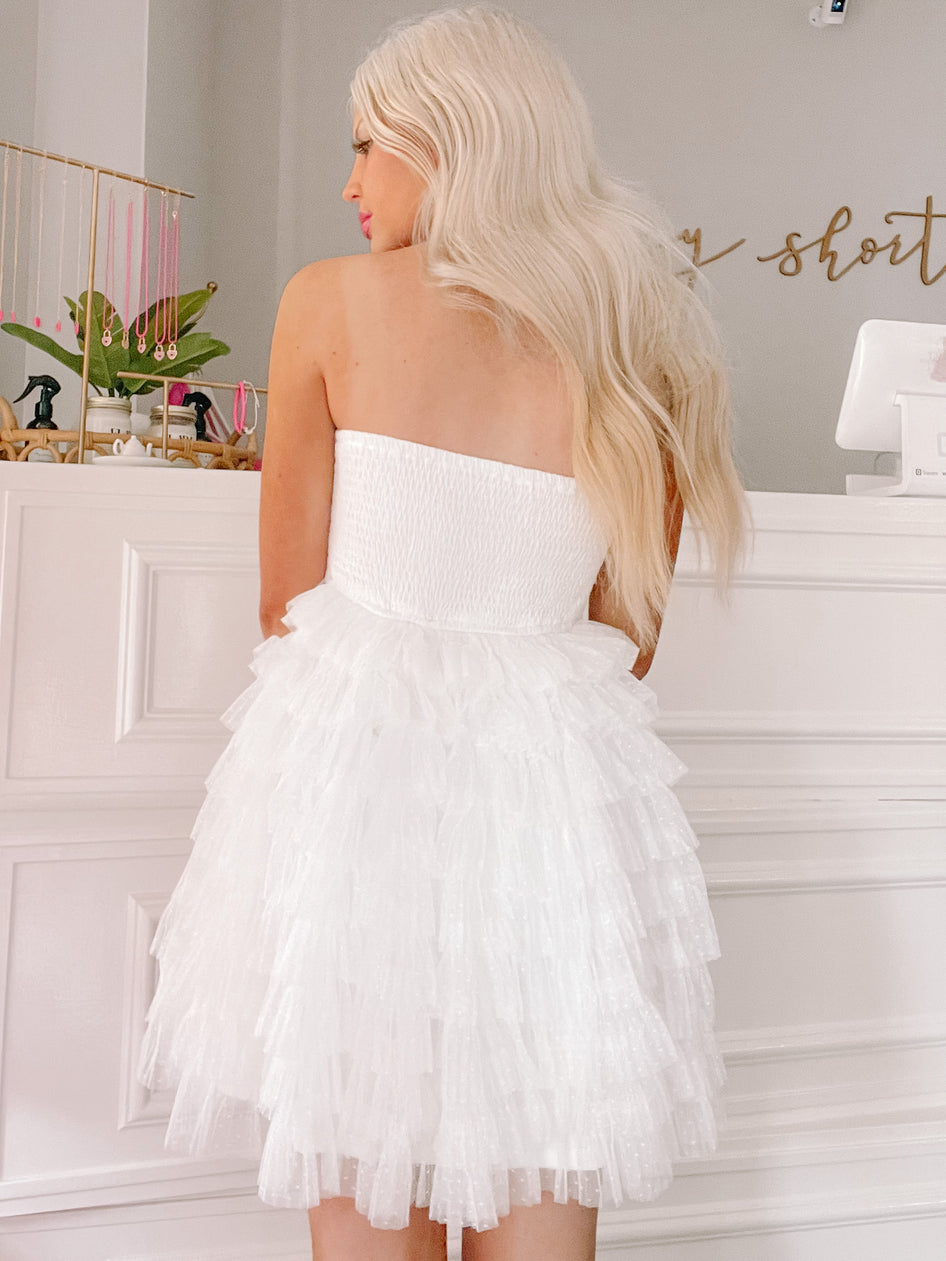White strapless mini dress with layered ruffles, shown from the back against a white backdrop.
