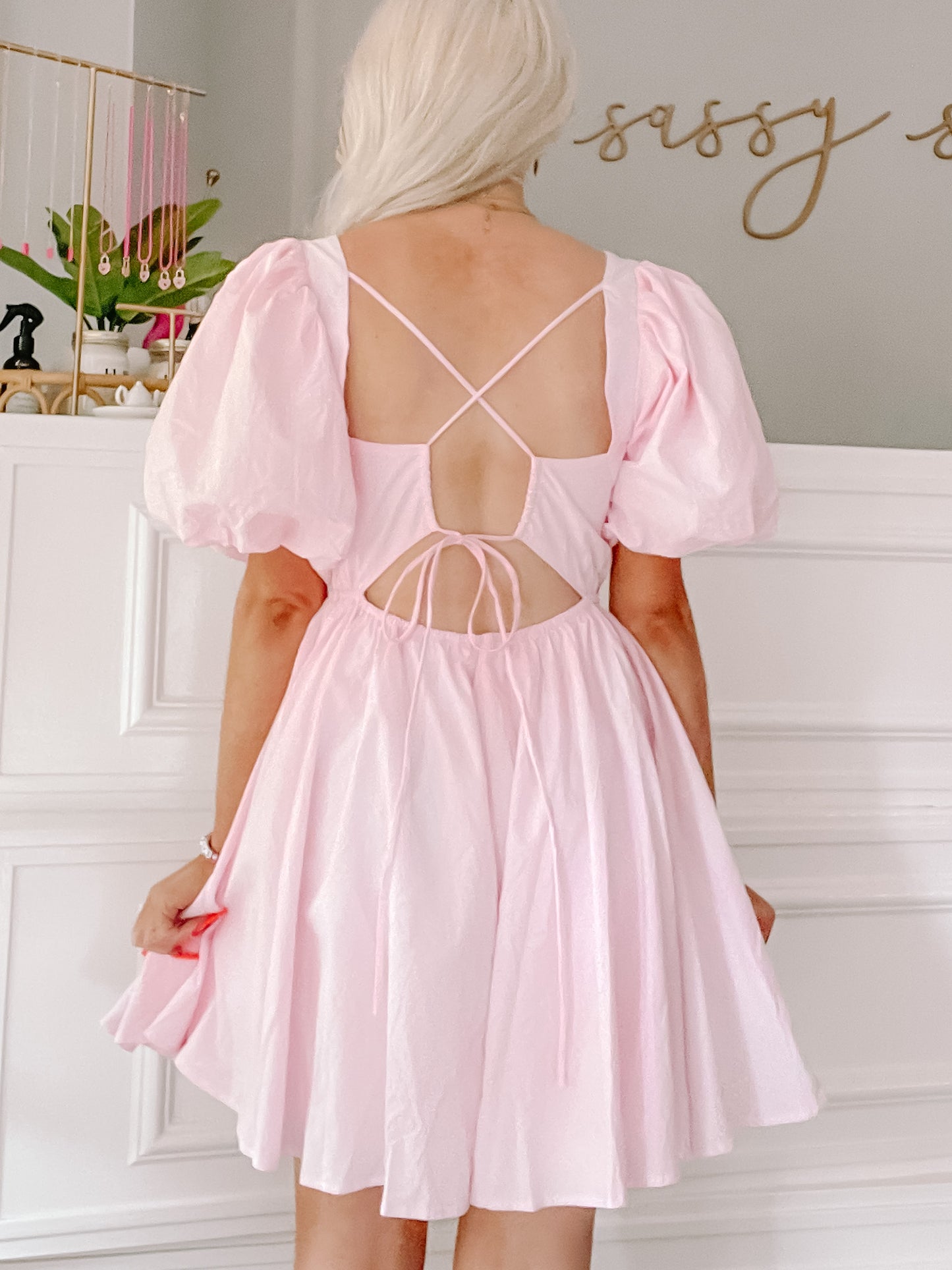 Pink mini dress with puff sleeves and an open back, shown on a model.
