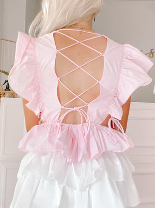 Pink ruffled top with a crisscross back detail and layered white ruffle bottom.
