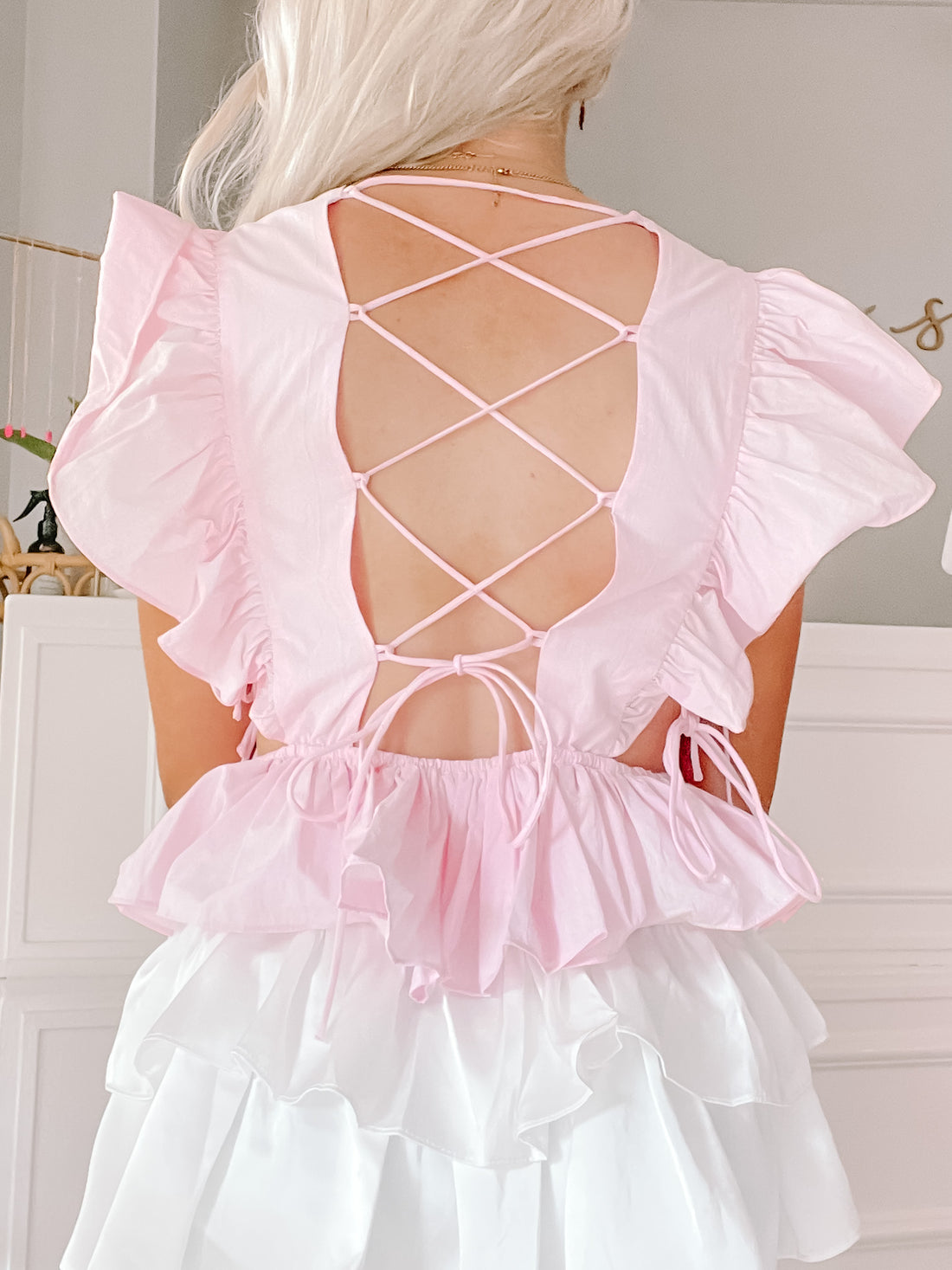 Pink ruffled top with a crisscross back detail and layered white ruffle bottom.
