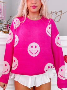 Hot pink knit sweater adorned with playful white smiley faces.
