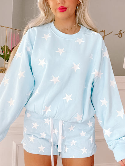 Light blue star-print shorts with a drawstring waist, shown paired with a matching top.
