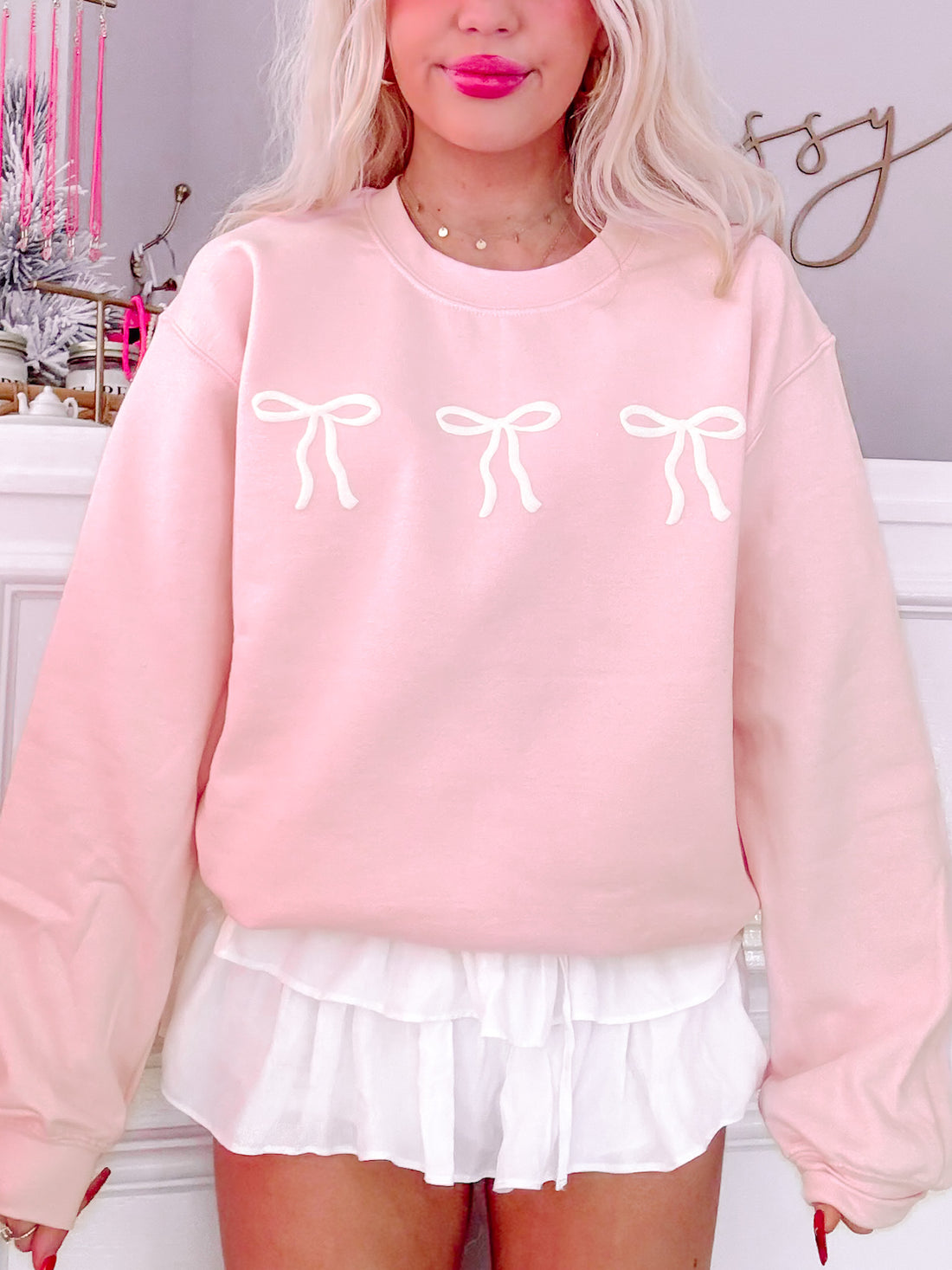 Blushing Bow Crewneck rose pink sweatshirt with three white bows.
