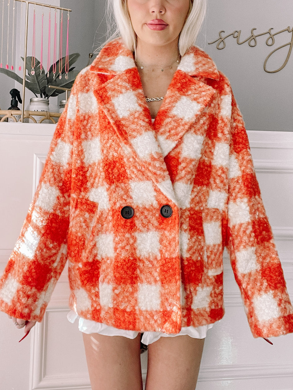 Orange and white gingham fleece jacket, double-breasted, modeled against a white wall.
